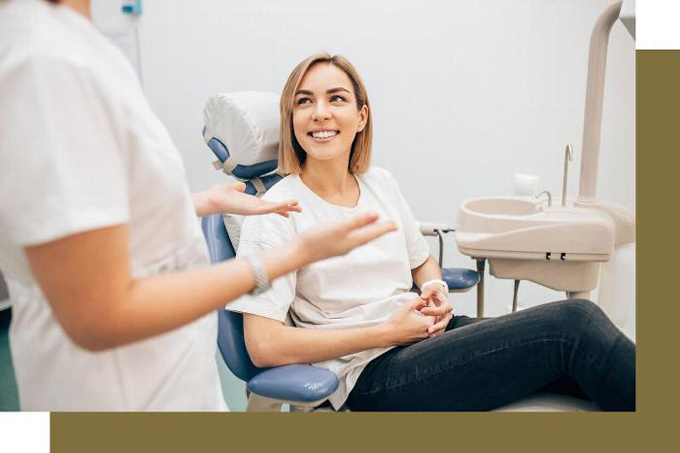 woman in dental chair smiling at dentist whilst talking
